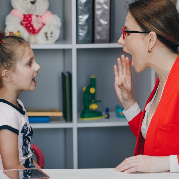 Cute little girl at speech therapist's office. Small child practicing articulation with therapist at private lesson at home.