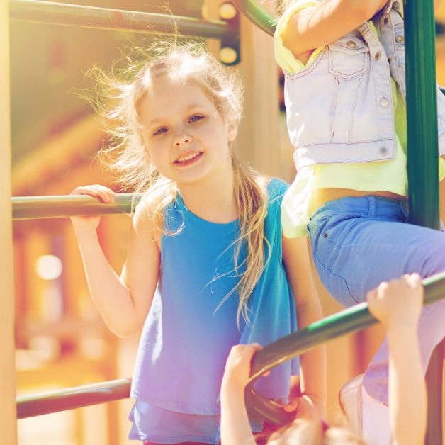 summer, childhood, leisure, friendship and people concept - group of happy kids on children playground climbing frame